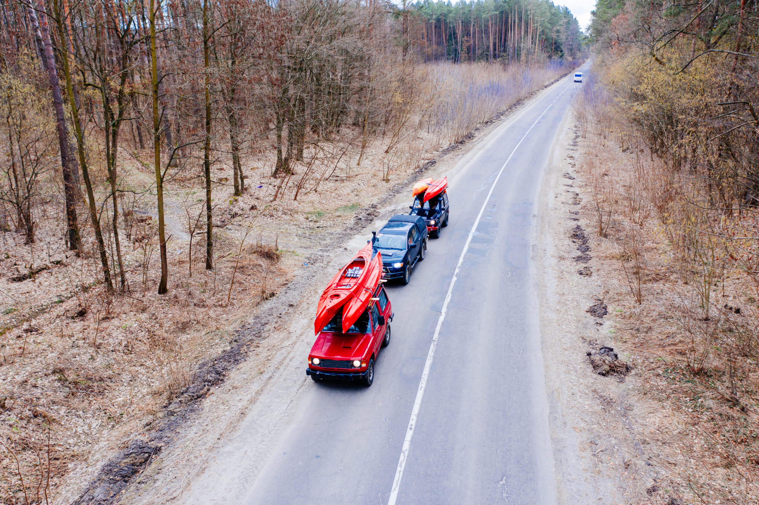several-cars-with-kayaks-roof-rack-driving-road-trees (1)